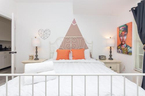 Dormitorio blanco con cama blanca y almohadas de color naranja en Home Midtown Miami - Wynwood area with backyard - Art District near to Beach, en Miami