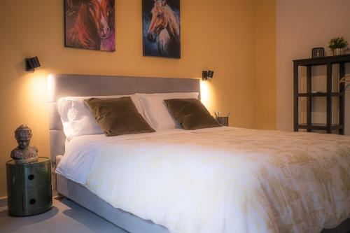 a bedroom with a white bed with a horse picture on the wall at Il Verdi home in Caserta