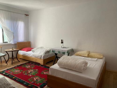 1 dormitorio con 2 camas, mesa y alfombra en North Gate Guest House and Camping en Shkodër