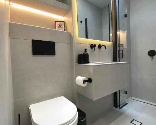 ein Badezimmer mit einem WC, einem Waschbecken und einem Spiegel in der Unterkunft Sand by Aestas Suites in Artemida