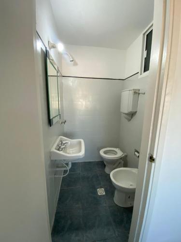 a white bathroom with two toilets and a sink at Vista a Montevideo in Montevideo