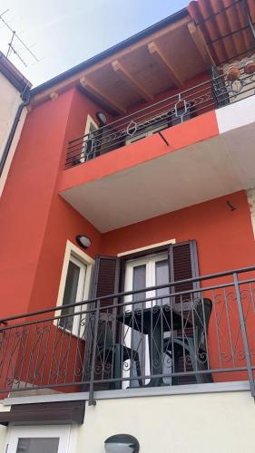 a red building with a balcony with black shutters at B&B Da Nora in Mallare