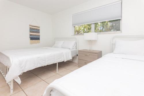 2 bedden in een witte kamer met een raam bij One Bedroom Apartment - with Parking & Balcony - Heart of Wynwood in Miami