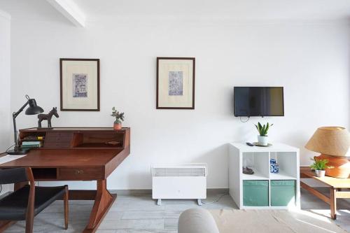 ein Wohnzimmer mit einem Schreibtisch und einem TV in der Unterkunft Sintra Sweet Apartment I - Free Parking in Sintra