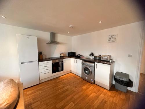 a kitchen with white cabinets and a washer and dryer at Joe Kelly Buildings B in Withernsea