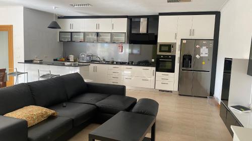 a living room with a black couch and a kitchen at Sorte do Castelo in Marco de Canavezes