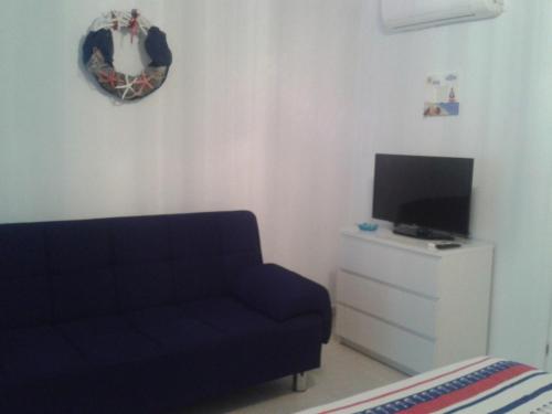 a living room with a blue couch and a tv at Rudi Studios in Sarti