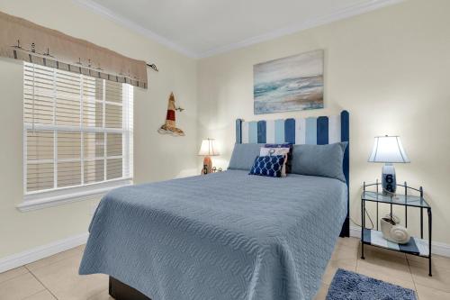 een slaapkamer met een blauw bed en een raam bij Rain Dancer in South Padre Island