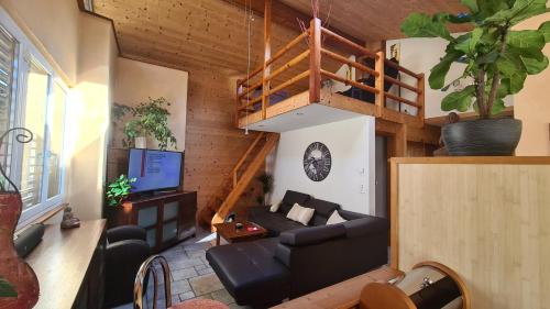 ein Wohnzimmer mit einem Sofa und einer Treppe in der Unterkunft Chez Pewee, beau duplex en ville, parc privé in Martigny-Ville
