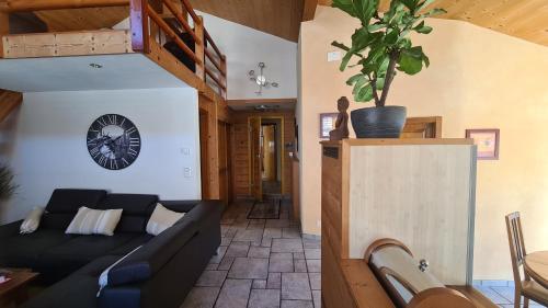 a living room with a couch and a clock on the wall at Chez Pewee, beau duplex en ville, parc privé in Martigny-Ville