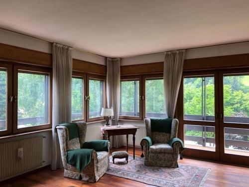 ein Wohnzimmer mit Stühlen, einem Tisch und Fenstern in der Unterkunft VILLA ADA (Val di Sole, Cogolo di Peio) in Cogolo