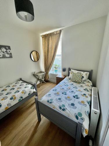 a bedroom with two beds and a window at The Blue Door in Kirkcudbright