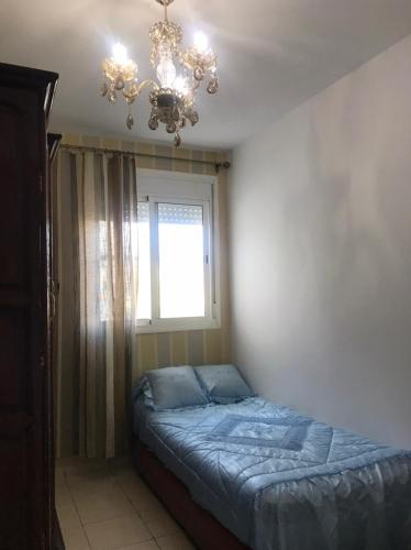 a bedroom with a bed and a chandelier and a window at Ceuta fnideq in Fnidek