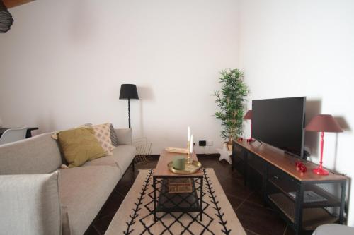 uma sala de estar com um sofá e uma televisão de ecrã plano em Birdy House em Faro