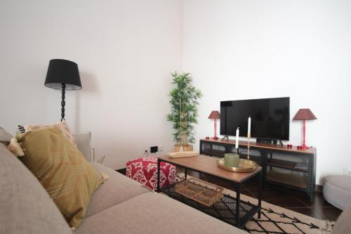 a living room with a couch and a table with a tv at Birdy House in Faro