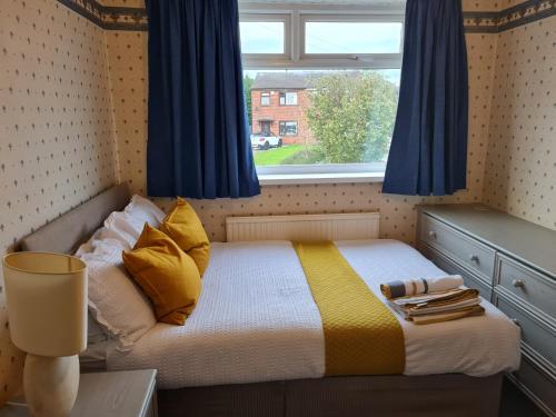 a small bedroom with a bed with blue curtains and a window at Immaculate 3-Bed House with free parking in Bolton in Bolton