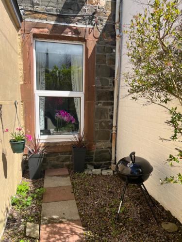 a garden with a grill in front of a window at The Blue Door in Kirkcudbright