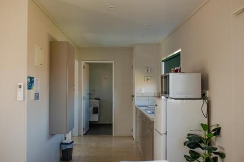 a kitchen with a white refrigerator and a hallway at Taupo TOP 10 Holiday Park in Taupo
