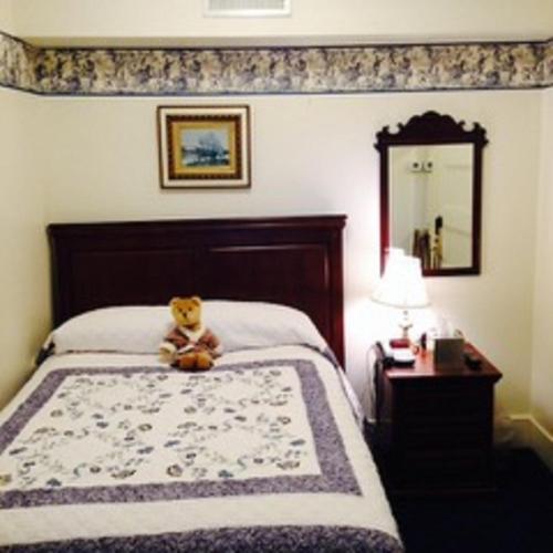 a teddy bear sitting on a bed in a bedroom at Gateways Inn in Lenox