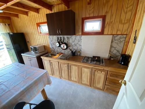 a kitchen with wooden cabinets and a stove top oven at Cabaña casa 6 personas, con vista al mar in Dalcahue