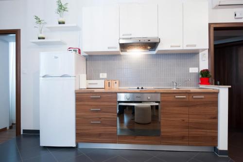a kitchen with a white refrigerator and wooden cabinets at Rooms & Apartments 72 in Zadar