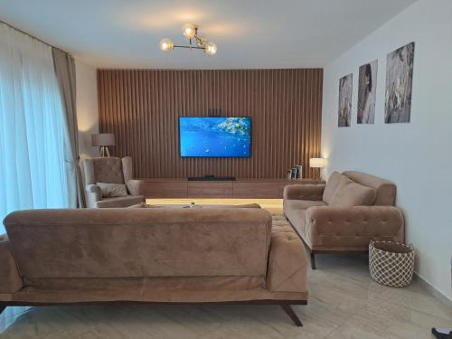 ein Wohnzimmer mit einem Sofa, 2 Stühlen und einem Flachbild-TV in der Unterkunft Lux Apartment Jovanovic in Tivat