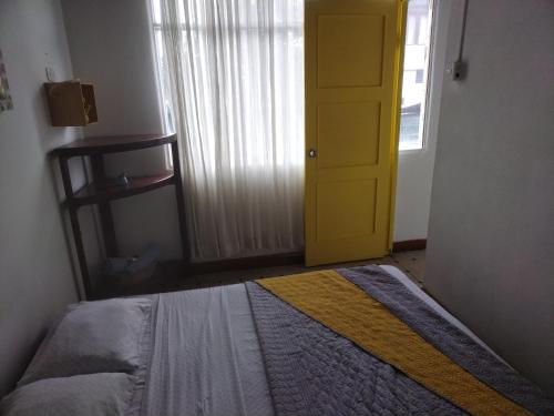 a bedroom with a bed and a yellow door at Hotel Cortez Azul in Alajuela City