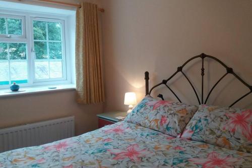 a bedroom with a bed with a floral bedspread and a window at The Stables, 2 Plough Square in Glanton