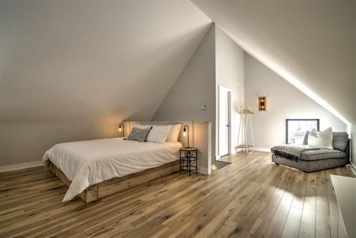 a white bedroom with a bed and a chair at Chalet Haut-Bois - Hiking, Skiing and Spa in Morin Heights