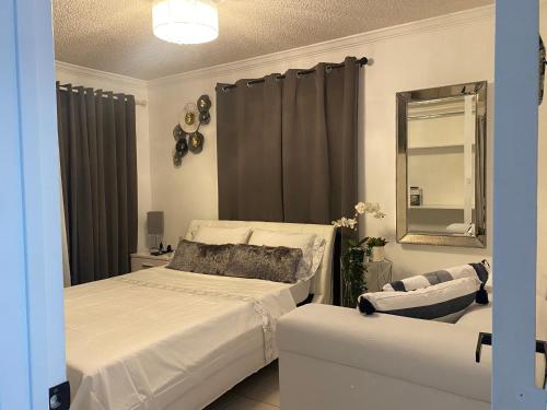 1 dormitorio con cama, espejo y silla en Beautiful House 7 min from Miami Airport w FREE parking en Miami