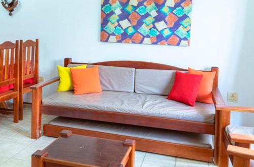 a living room with a couch with colorful pillows at Res Village do Bosque 03 in Porto Seguro