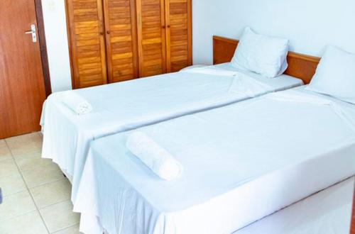 two beds in a hotel room with white sheets at Res Village do Bosque 03 in Porto Seguro