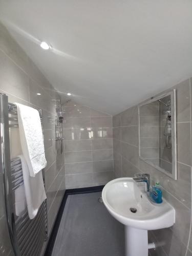 a white bathroom with a sink and a shower at NO 27 Apartment in Llandudno