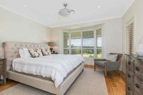 een slaapkamer met een bed, een stoel en een raam bij Cullengetty Estate in Berry