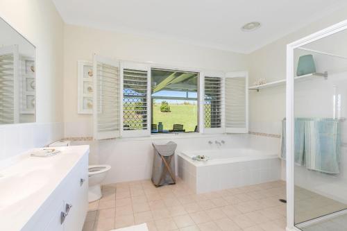 a white bathroom with a tub and a toilet at Cullengetty Estate in Berry