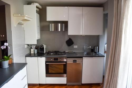 a kitchen with white cabinets and a sink and a stove at Collegio di Spagna 13 in Bologna