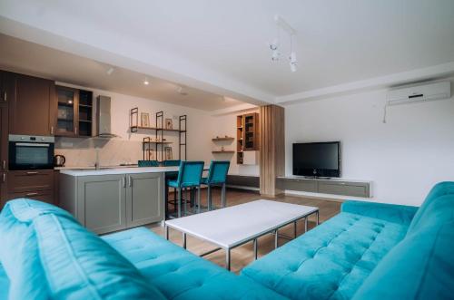 a living room with a blue couch and a kitchen at Darki Comfort Apartments - Stylish Apartments with Free Parking in Tranquil Area in Ohrid