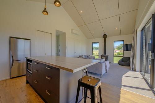 a kitchen with a large island and a living room at Schist Cabin in Twizel