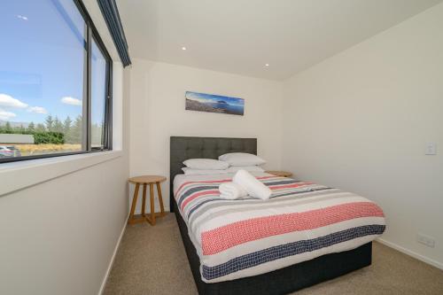a bedroom with a bed with a window at Schist Cabin in Twizel