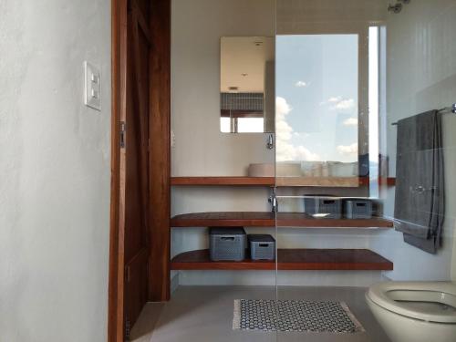 a bathroom with a toilet and a glass wall at Casa Prosperidade in Alto Paraíso de Goiás