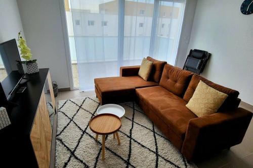 salon z brązową kanapą i stołem w obiekcie Appartement avec balcon/terrasse w mieście Monteux