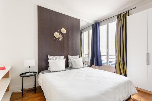 - une chambre avec un grand lit blanc et des rideaux bleus dans l'établissement Luxury Living in Passy, à Paris
