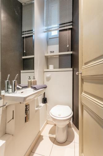 une salle de bain blanche avec des toilettes et un lavabo dans l'établissement Luxury Living in Passy, à Paris