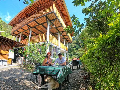 a man and woman sitting at a table with a dog at Termales el Escondite in Florencia
