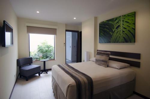 ein Schlafzimmer mit einem Bett und einem Stuhl und einem Fenster in der Unterkunft Isla Verde Hotel in San José