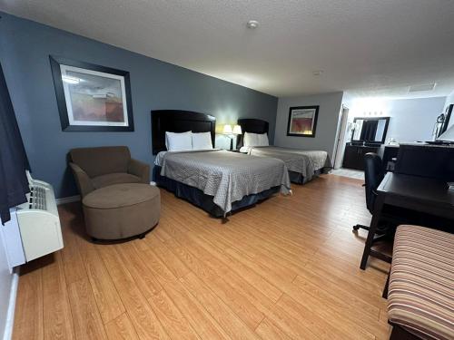 a bedroom with two beds and a chair and a piano at Kenora Motel in Windsor