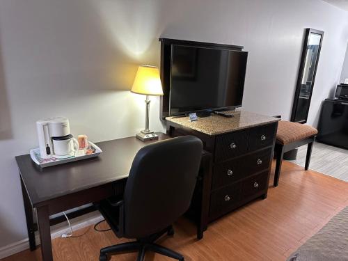 a room with a desk with a television and a chair at Kenora Motel in Windsor
