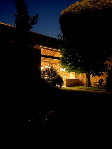 a building with a tree and a bench at night at La Planque - Chambres avec Jacuzzi in Fleury-en-Bière