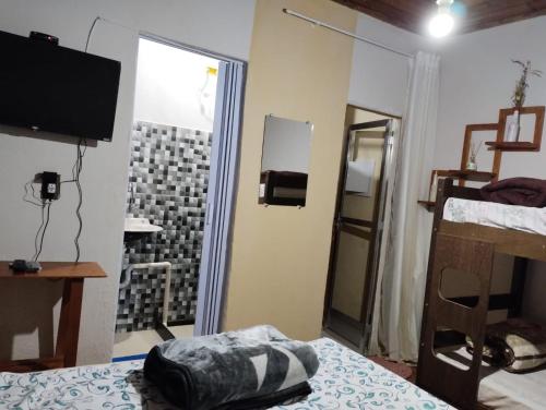 a room with a bedroom with a bed and a tv at Hospedagem Roze - in São José de Pedra Menina