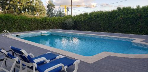 a swimming pool with blue chairs next to at Férias felizes em família/com amigos in Março de Simães